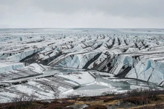 Glacier arctique en fort recul exposant la roche noire sous-jacente, symbole visible du changement climatique et de la fonte des glaces polaires